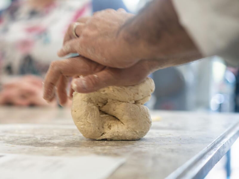 Hands kneading dough on a floured surface